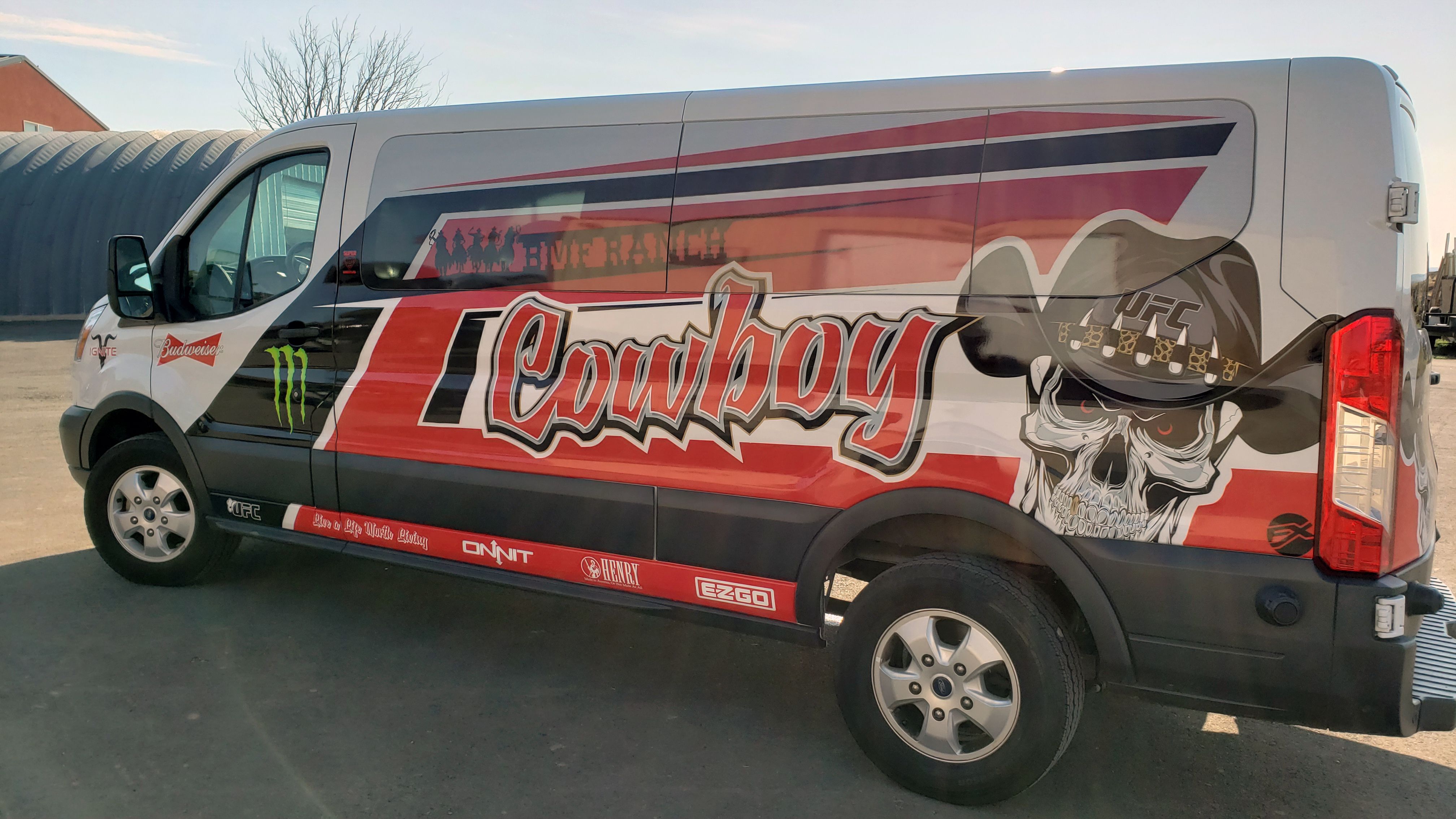 A commercial work van with a custom vinyl wrap with white, red, and black logos and text with a cowboy UFC design