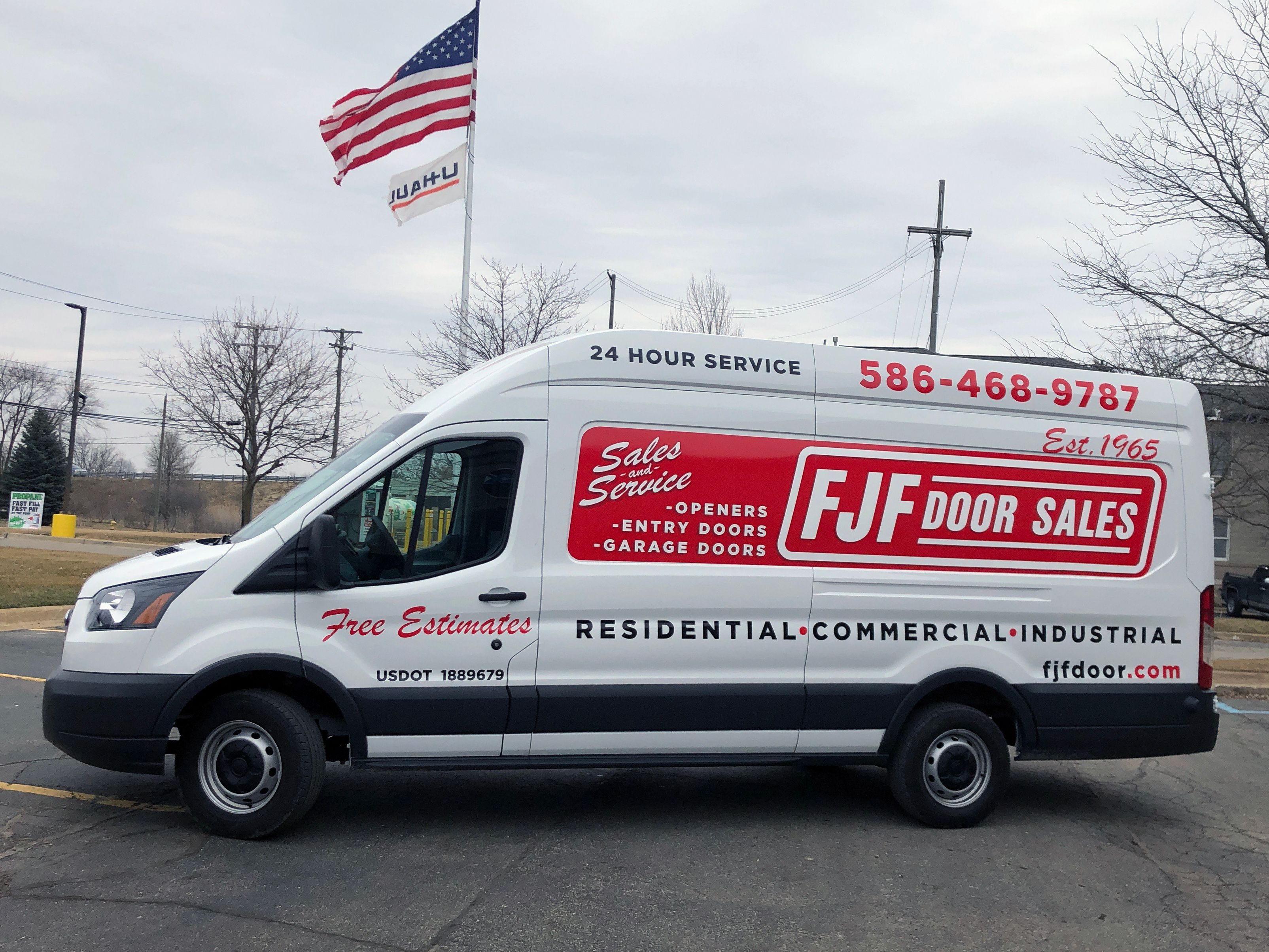 A commercial work van with a custom vinyl wrap with white, blue, and red logos and text