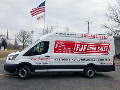 A commercial work van with a custom vinyl wrap with white, blue, and red logos and text