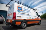 A commercial work van with a custom vinyl wrap with white, blue, black and orange logos and text
