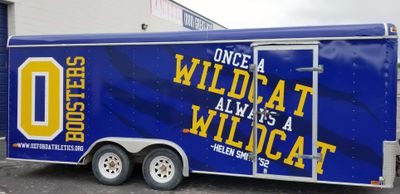 A commercial trailer with a custom vinyl wrap with yellow, blue, and white logos and school design.