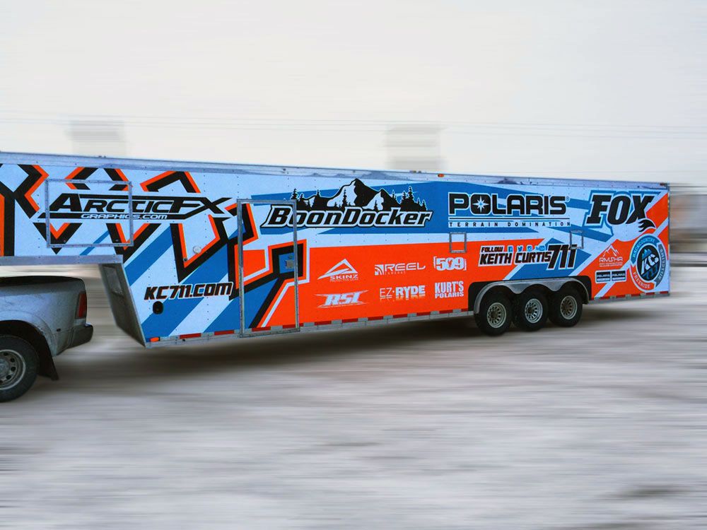 A snowmobile trailer with a custom vinyl wrap with bright orange, white and blue shapes and lines.