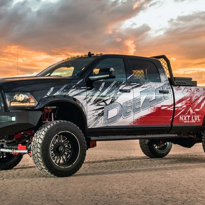 A commercial work truck with a custom vinyl wrap with red, white, and black logos and text with a grunge design