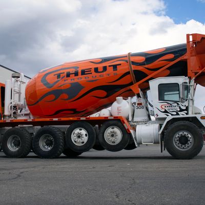 A commercial cement truck with a custom vinyl wrap of black and gray flames and logos on the barrel