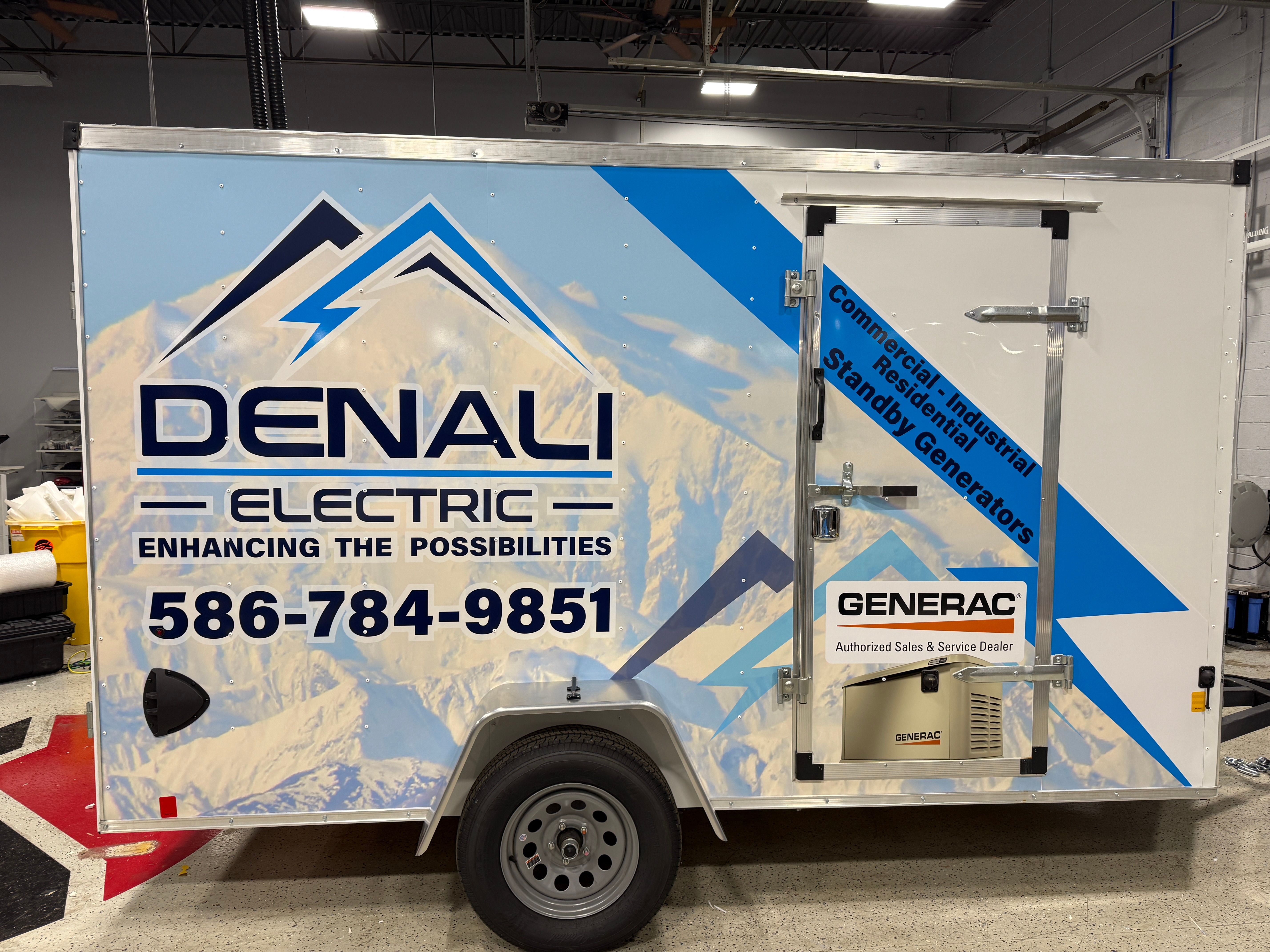 A commercial box trailer with a custom vinyl wrap with a blue and white mountain themed design
