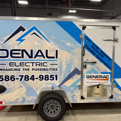 A commercial box trailer with a custom vinyl wrap with a blue and white mountain themed design