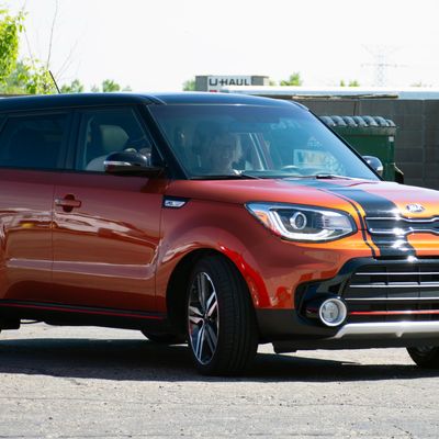 A personal kia car with a custom black accent stripe across the hood and roof